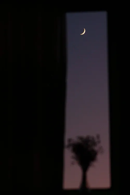 Image d'ambiance : un croissant de lune dans une fenêtre étroite, la nuit