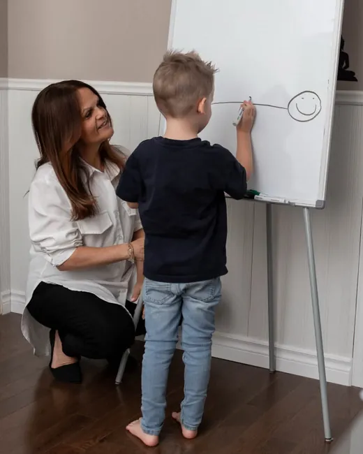 Line Gagné, accroupie près d'un enfant qui dessine au tableau blanc