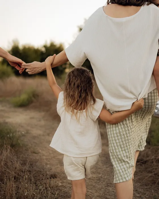 Image d'ambiance : une maman et sa fille, main dans la main, de dos, sur un sentier
