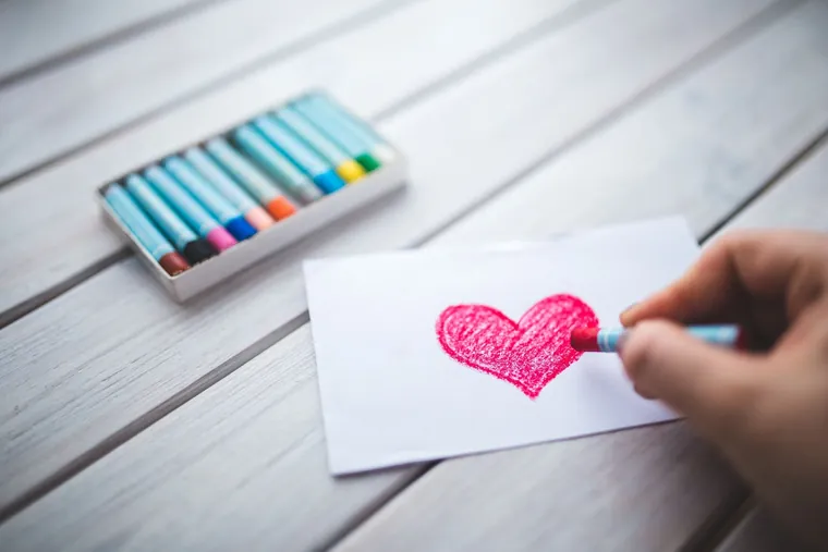 Image d'ambiance : une main qui dessine un cœur rose aux pastels